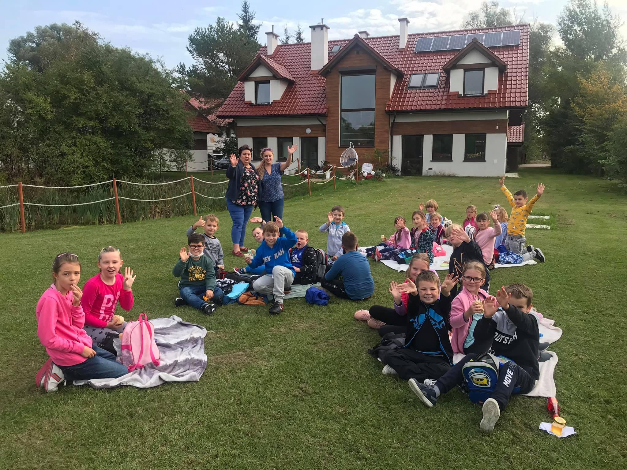 Small children sitting on the grass in front of a building