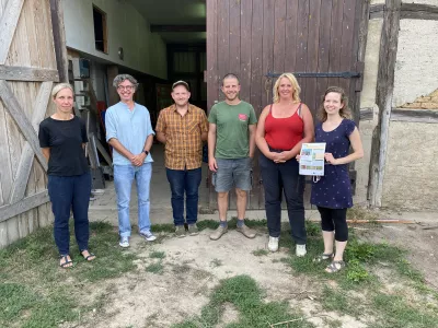 A group of people pertaining to the Operational Group at Weggun Farm posing in front of a barn