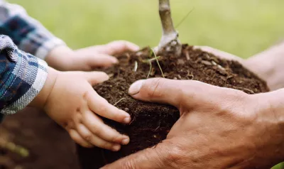A toddler and an adult person holding earth together