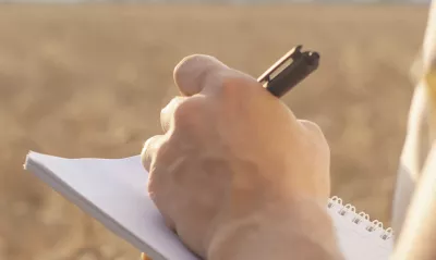 A person taking notes on a notebook in a field