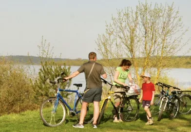 A family with their bikes in front of a lake