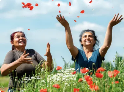 Two women throw flowers at the sky in a poppy field