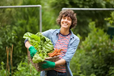 A woman holding a basket of vegetables and smiling
