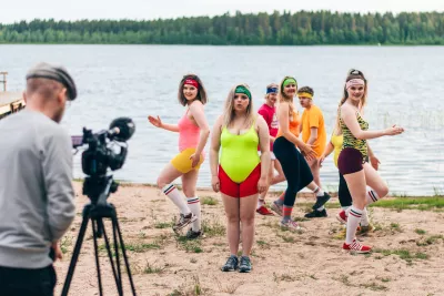 group of dancers in colourful clothes in front of a lake