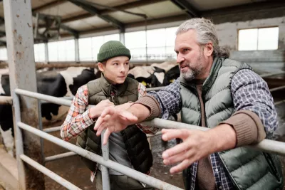 Farmer talking to a boy in a stable with cows