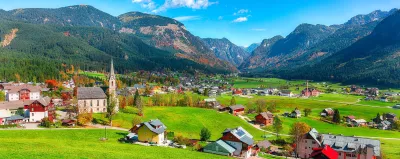 Alpine green fields and traditional wooden houses view of the Gosau village at autumn sunny day