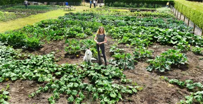 a woman standing in a garden with a dog