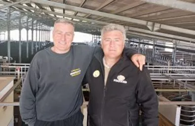Two men inside a barn smiling.