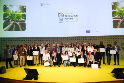 Large group of people showing certificates and tropies on stage