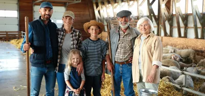Portrait of happy Caucasian family of three generations standing in shed with livestock and smiling