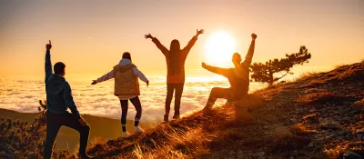 Group of happy friends are standing at mountain top
