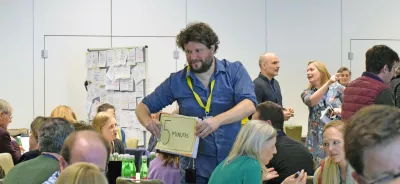 Facilitator holds up a sign to workshop participants, the sign says '5 minutes'