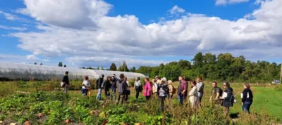 A group of people standing in a field next to a greenhouse