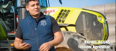 Young farmer Rafael Aguas talking in front of a tractor