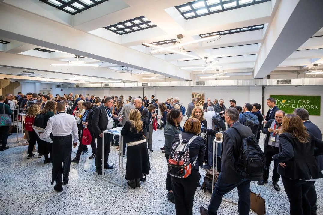 A group of people networking in a big room at EU CAP Network