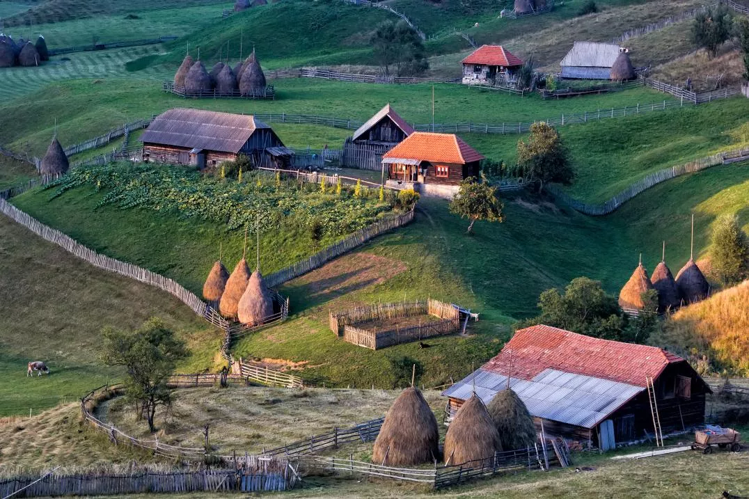 A group of houses on a green hill, it represents small farms in Romanian 