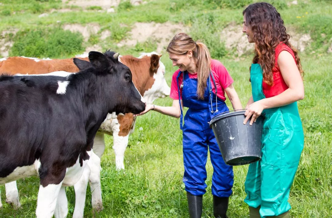 A group of women in overalls with a bucket of milk