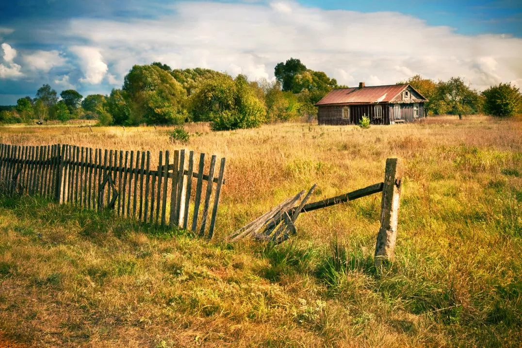a fence in a field with a barn in the background
