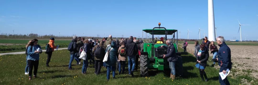 A group of people around a tractor in an eolic park