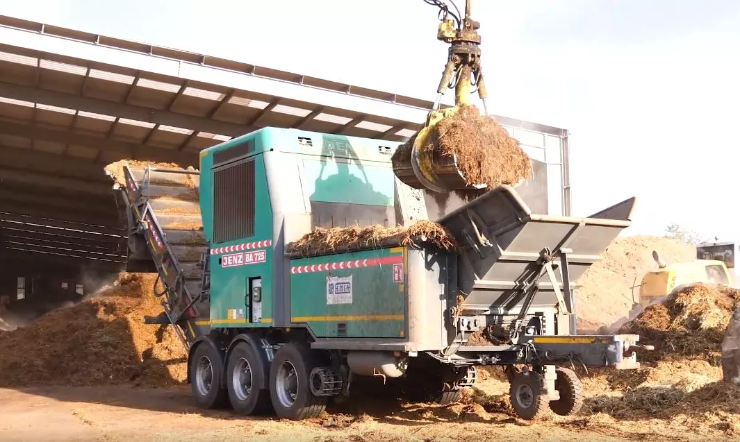 a large truck with a crane loading hay into it