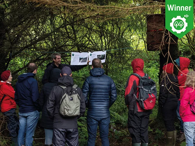 a group of people looking at a paper in a forest