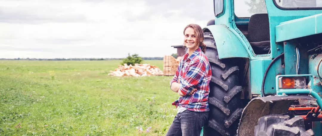 Young beautiful girl working on a tractor in the field