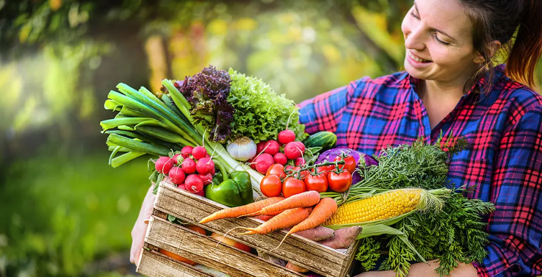 Woman carrying a box of vegetables