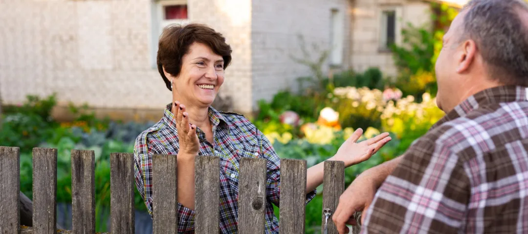neighbors man and woman chatting near the fence in the village