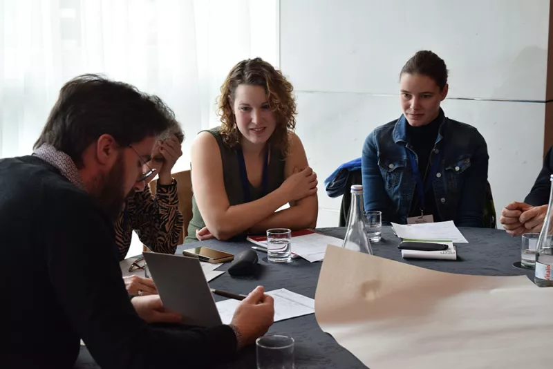 a group of people sitting around a table at the "Eu cap network launch event"