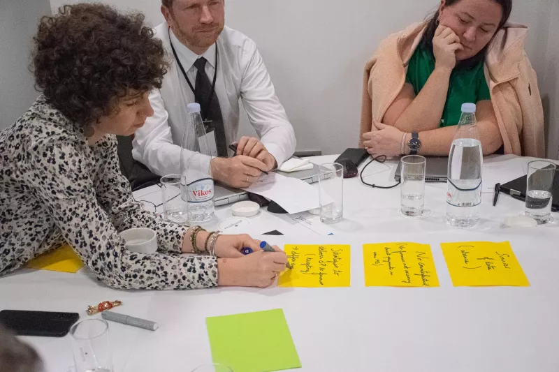 a group of people sitting at a table full of post-it at a workshop on "How to assess direct payment interventions in the new CAP"