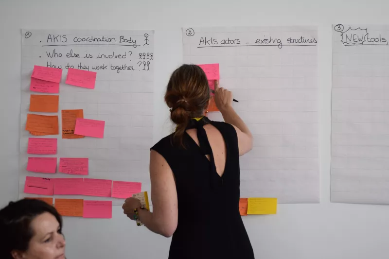 AKIS Seminar participant sticking post-its on a flipchart