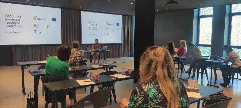 A group sits and watches a presentation about financial literacy