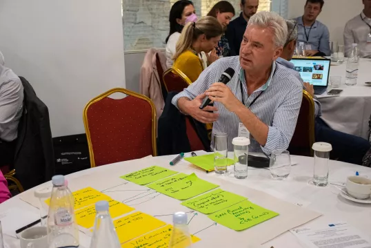 a man sitting at a table with a microphone at the workshop on "How to assess direct payment interventions in the new CAP"