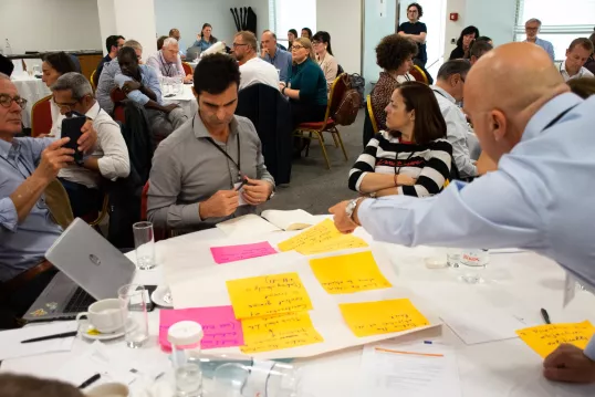 a group of people sitting around a table with yellow sticky notes at the workshop on "How to assess direct payment interventions in the new CAP"