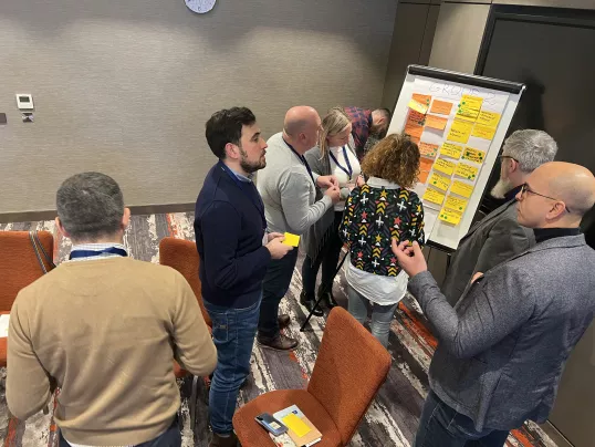 a group of people standing around a whiteboard at the "2022 eu cap network ws young entrepreneurs"
