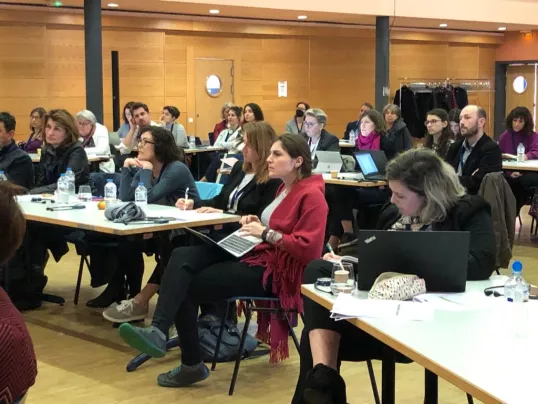 a group of people sitting at tables watching a presentation