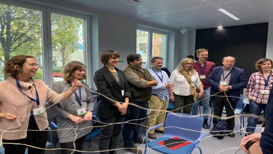 Group exercise with participants holding a network of strings