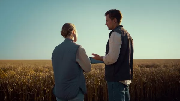 A man and a woman, both farmers, talking in a field